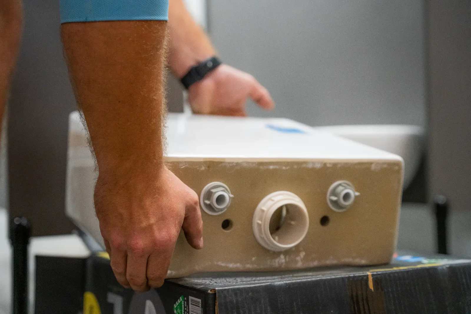 Plumber handling a new toilet cistern during an installation in a Queensland bathroom
